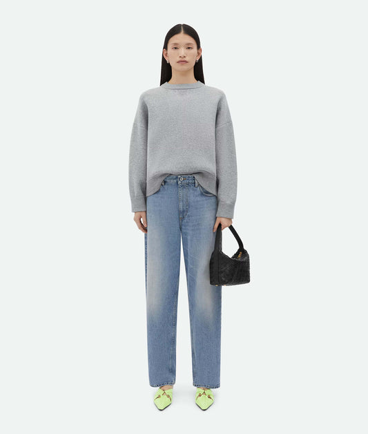 Woman wearing a gray sweater and blue jeans, holding a Bottega Veneta Mini Wallace Black 754443V3IV18425 on a white background