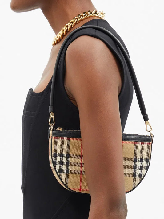 Person wearing a black sleeveless top with a gold chain, holding a Burberry Vintage Check Olympia Pouch In Canvas Archive Beige 81114131