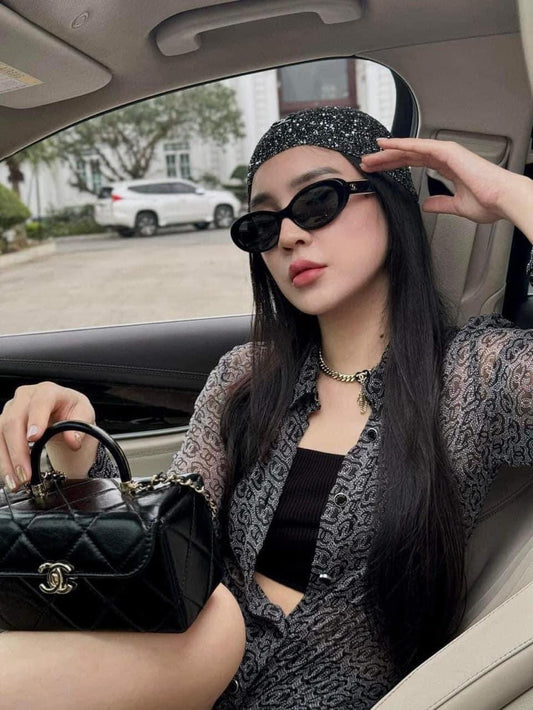 Woman sitting in a car holding a Chanel handbag, wearing Chanel CH5515 C62248 Sunglasses and a patterned headband.