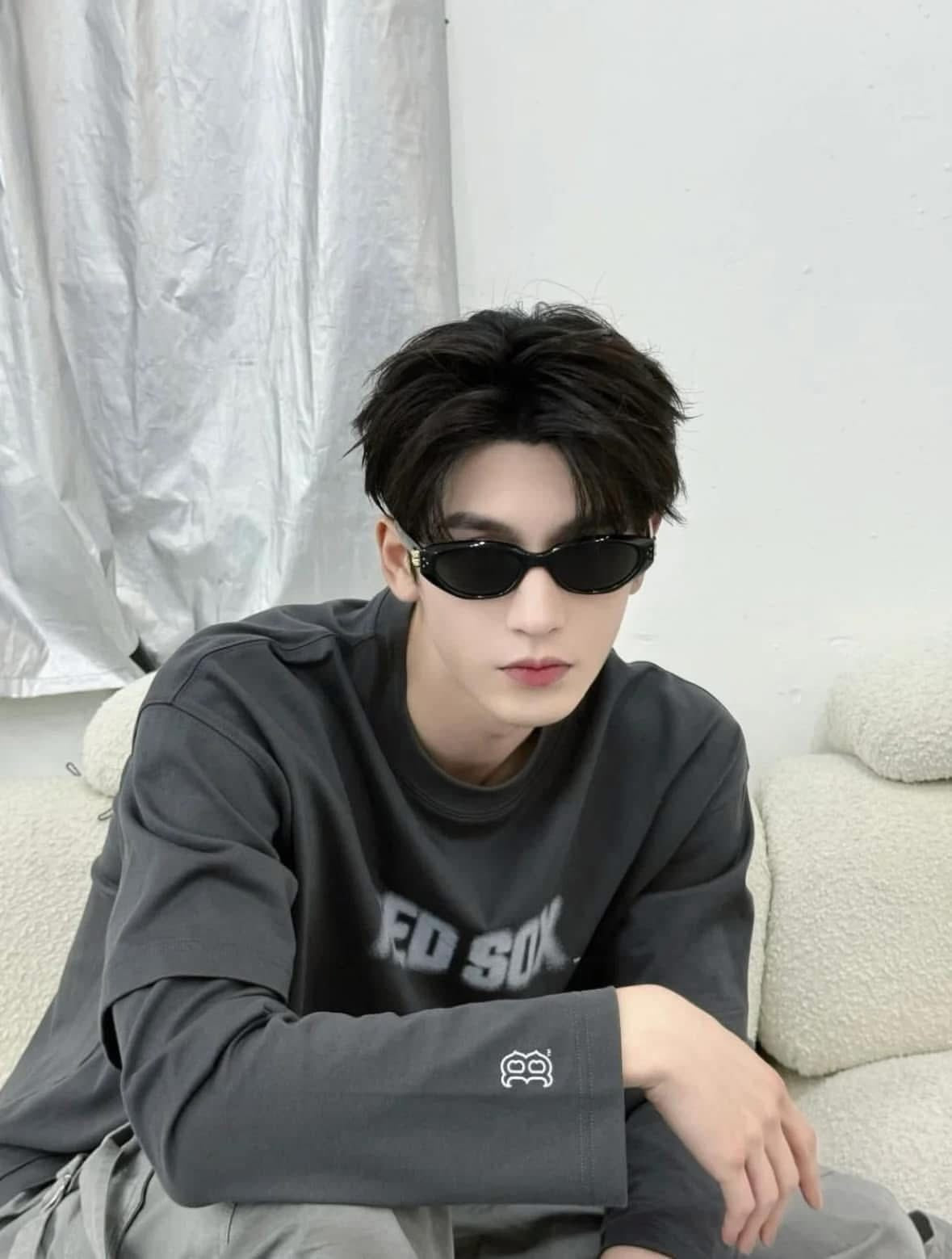 Man wearing Gentle Monster (GM) Duns 01 and a dark hoodie sitting on a couch.