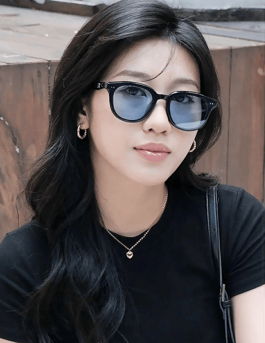 Woman wearing Gentle Monster - GM Jude 01(BL) with a wooden background