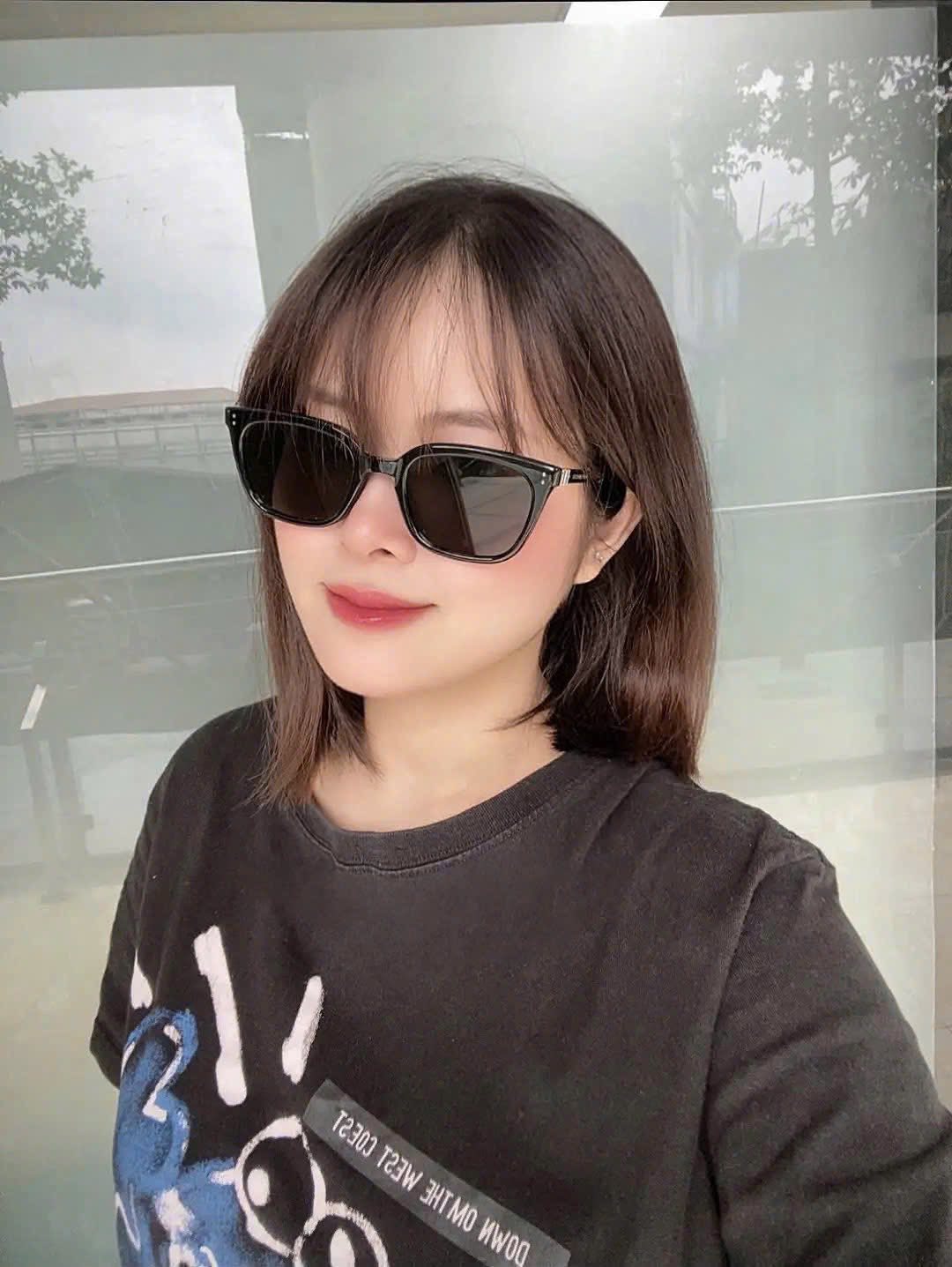 woman wearing Gentle Monster (GM) Matiny 01 and a black shirt with graphic designs indoors.