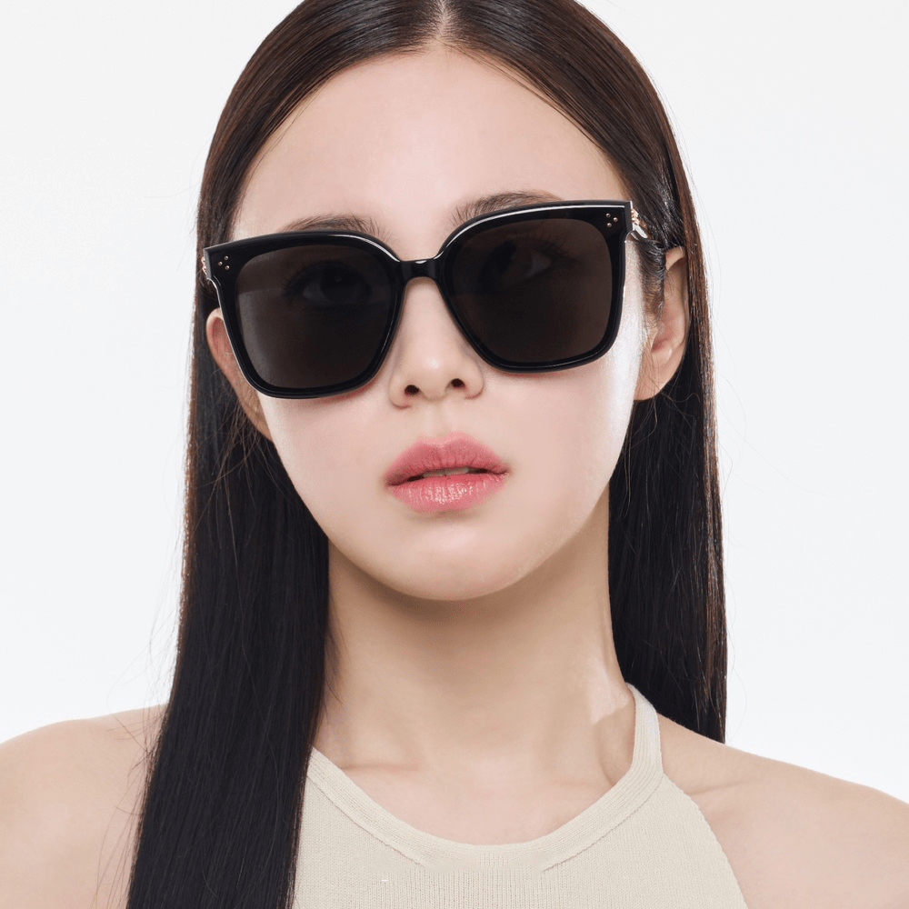 Woman wearing black sunglasses with a plain background