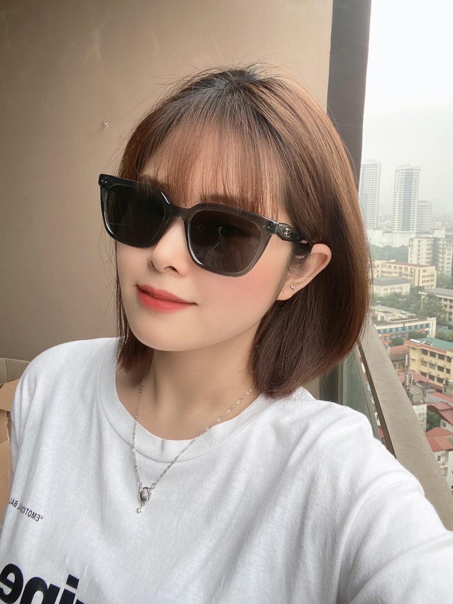 Person wearing Gentle Monster (GM) Nubo G3 with a cityscape in the background