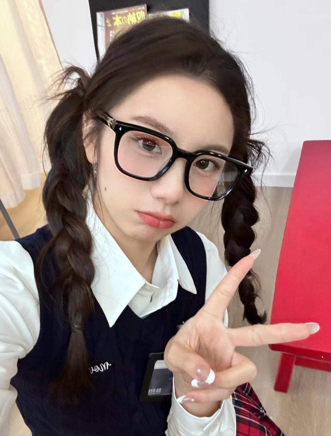 woman wearing Gentle Monster (GM) Ojo 01 and a school uniform, pointing with one finger indoors.