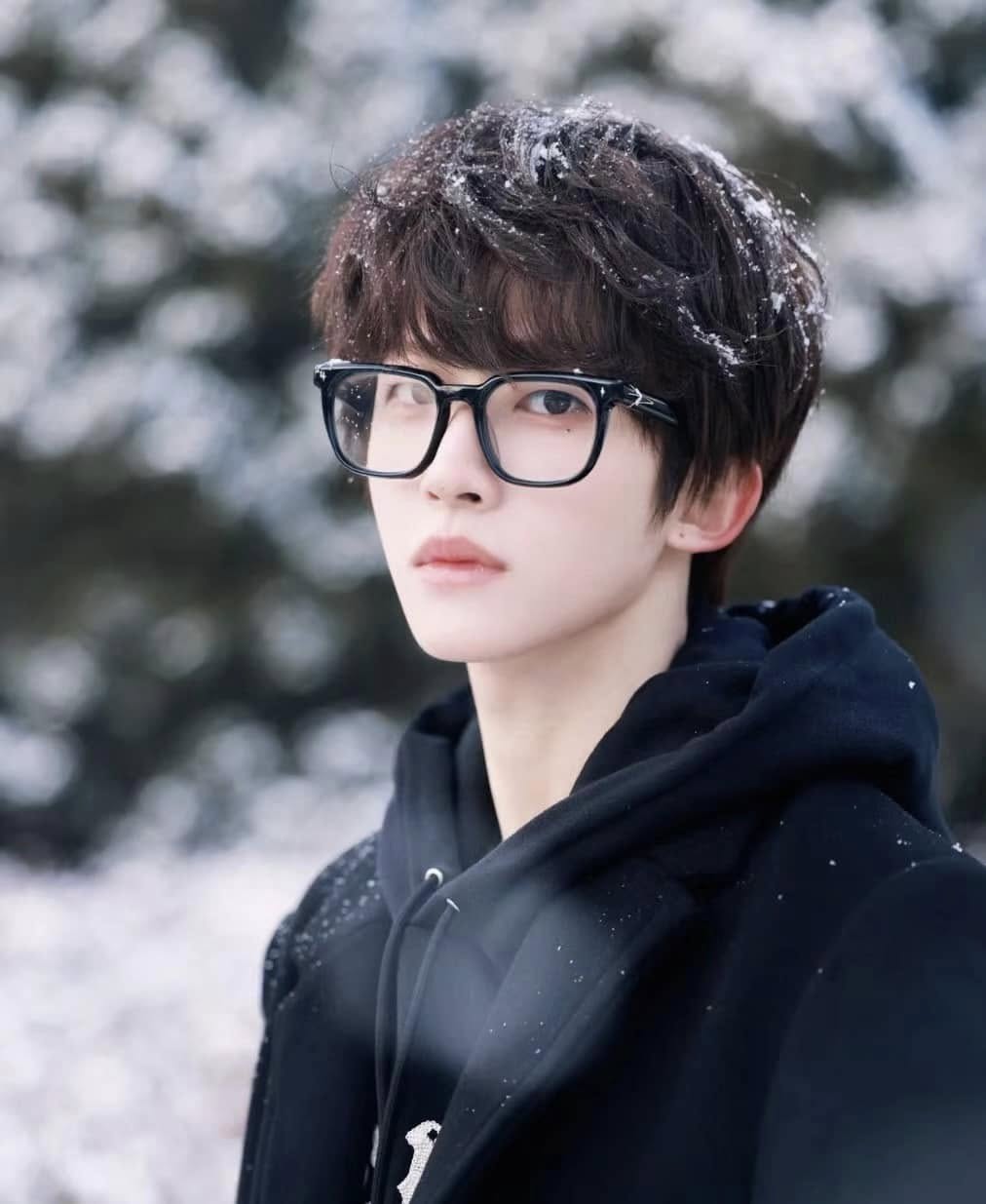 a man wearing Gentle Monster (GM) Ojo 01 and a black hoodie in a snowy outdoor setting