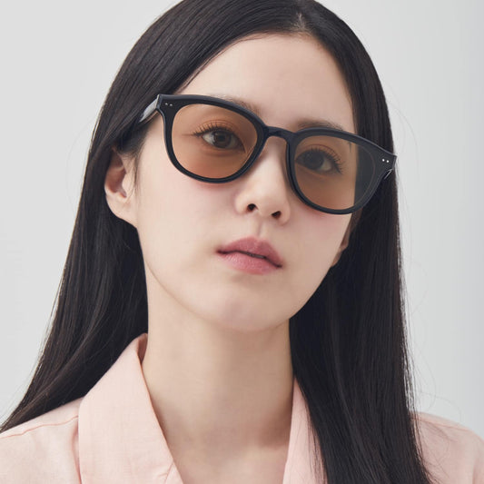 Women wearing Gentle Monster Jade 01(BR) Round Sunglasses with a plain background