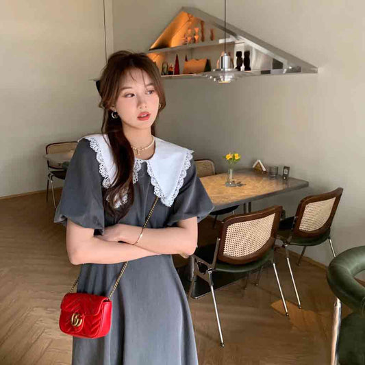 Woman in a gray dress with a Gucci GG Marmont Matelassé Mini Bag in Red Leather 476433 DTDHT 6832 in a modern interior setting