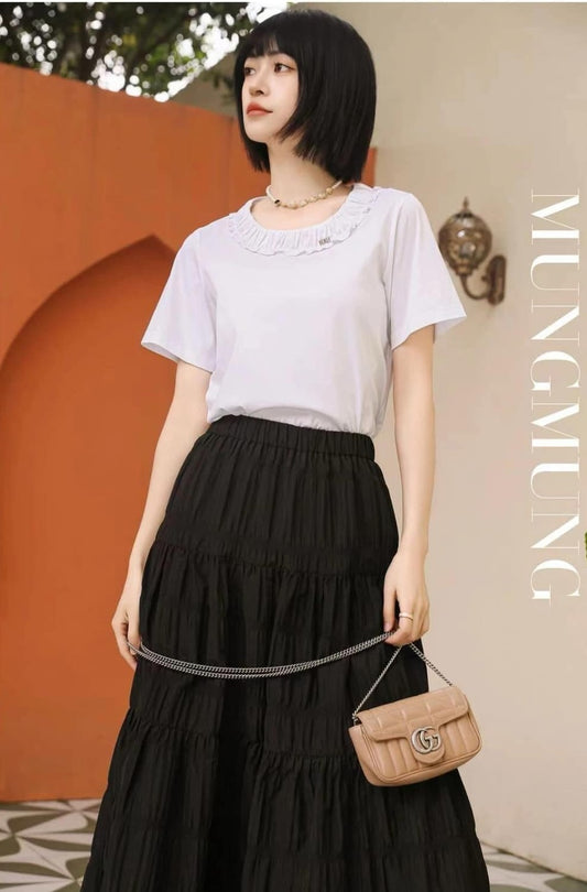 Woman wearing a white top and black skirt with a Gucci GG Matelassé Marmont Mini Bag Rose Beige 476433 DTD5N 2754 against an orange wall.