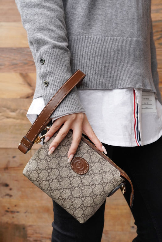 Person holding a Gucci Interlocking G Mini Messenger Bag Beige 723306 92THG 8563 with a wooden floor background