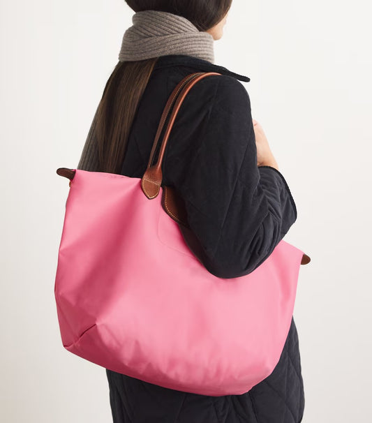 Person carrying a Le Pliage Original L Tote Bag Marshmallow L1899089P92 with brown handles on a plain background