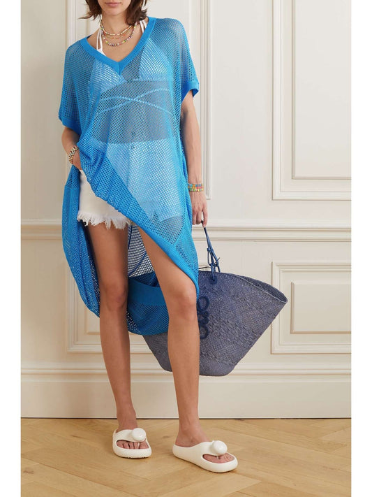 Woman wearing a blue mesh cover-up with white shorts and Loewe Paula Ibiza Foam Thong Slide White L616S03X02 2100, holding a blue bag indoors.