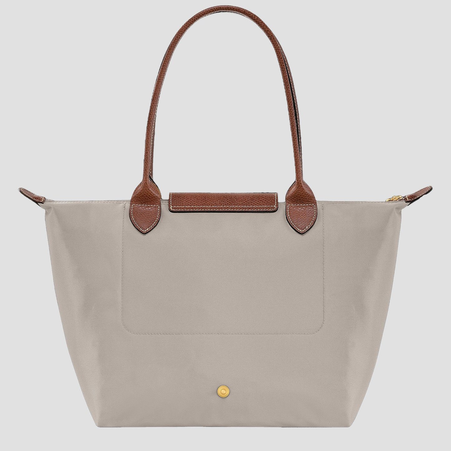 behind Longchamp Le Pliage Original M Tote Bag – Pebble L2605089349 with brown handles on a light gray background