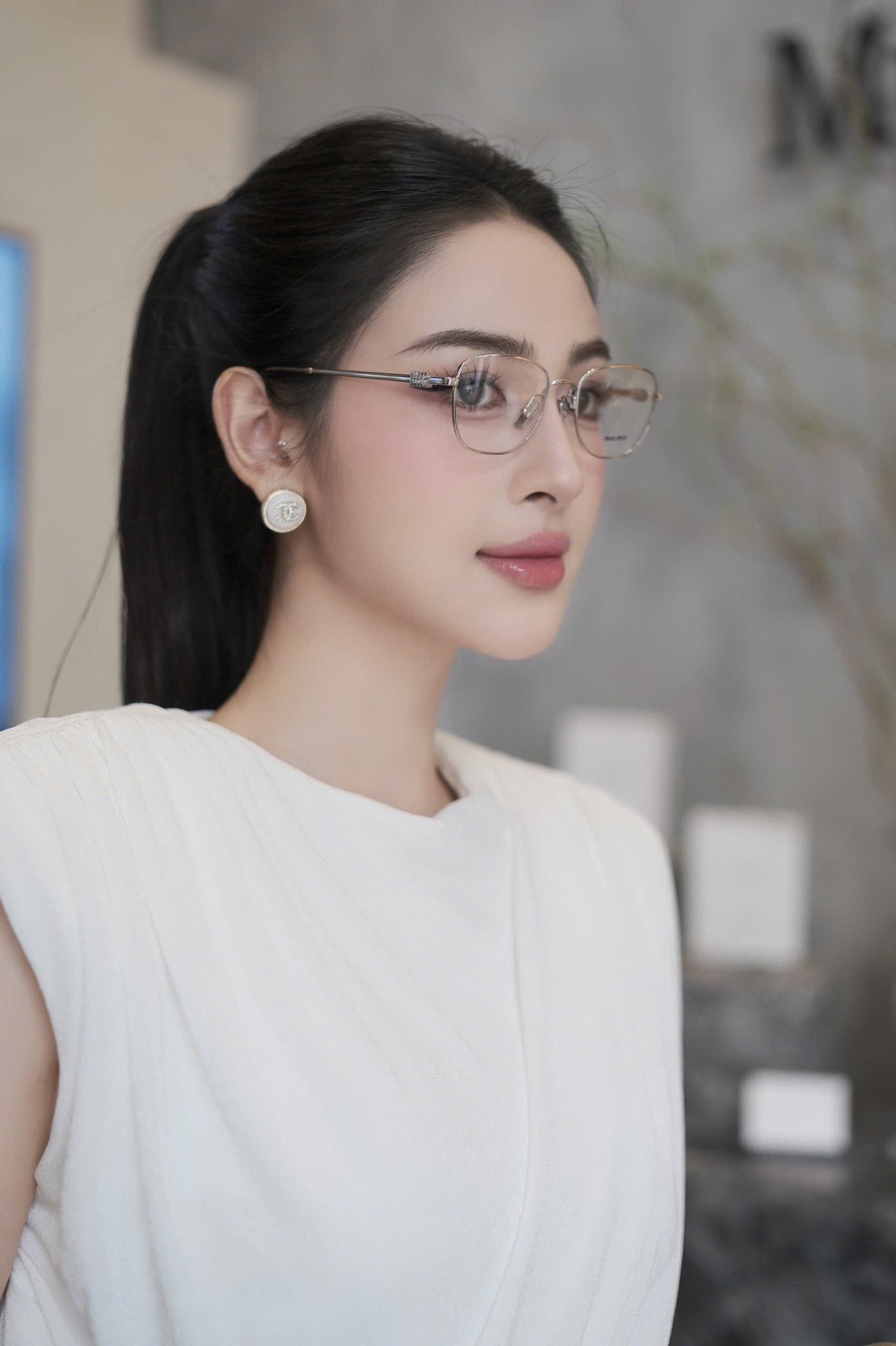Woman wearing Miu Miu MU 50WV 1BC1O1 Eyeglasses and a white top in an indoor setting