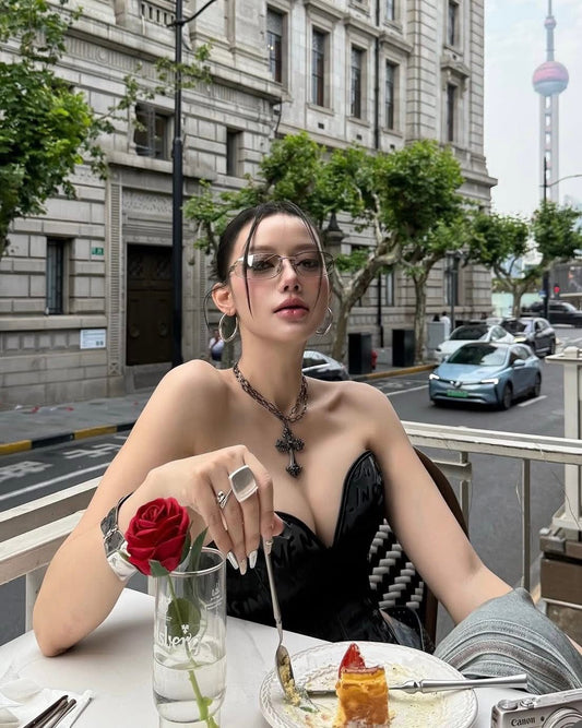 Woman wearing Miu Miu MU A50S 1BC8H1 Sunglasses sitting at an outdoor table with a cityscape background