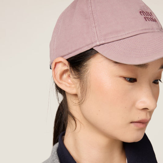 Person wearing a Miu Miu Raspberry Drill Baseball Cap 5HC370 2CR2 F0590 with a brand logo on a plain background