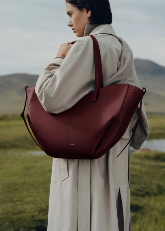 Person wearing a Polène Cyme Edition Textured Black Cherry in a scenic outdoor setting