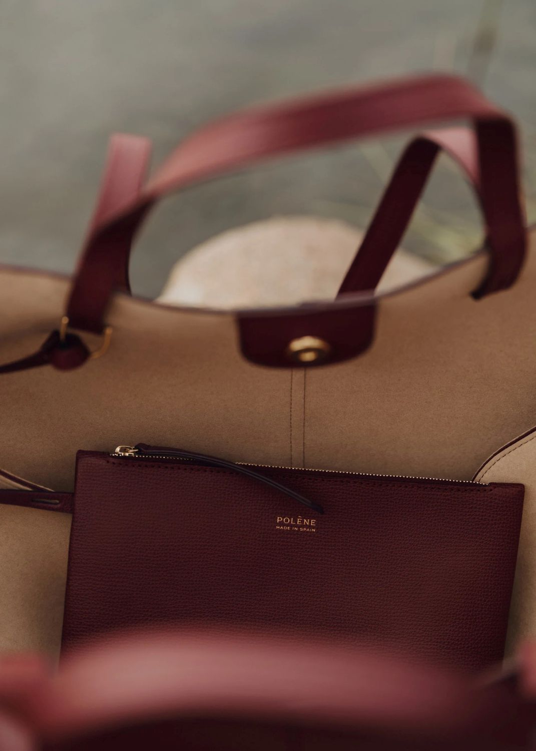 Open Polène Cyme Edition Textured Black Cherry with a matching pouch on a blurred background