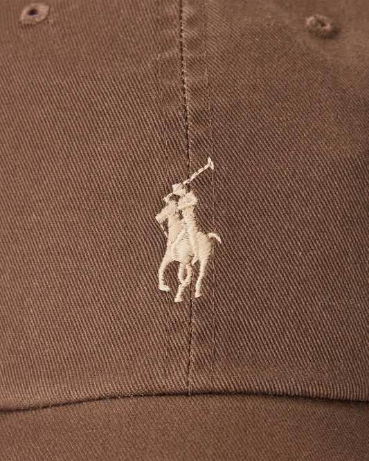Close-up of a brown cap with a white embroidered logo on a brown background