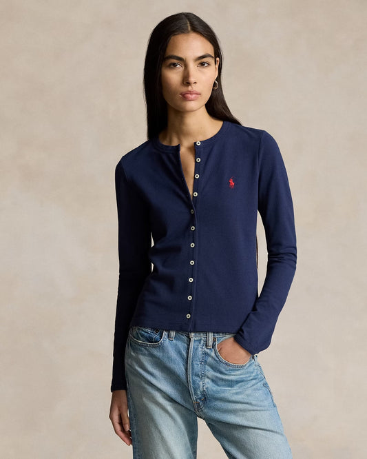 Woman wearing a Polo Ralph Lauren Stretch Mesh Cotton Crewneck Cardigan – Newport Navy 211941175003 with a red logo and light blue jeans against a beige background