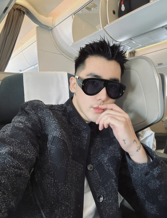 Person wearing Tom Ford Bronson FT1044 01A Sunglasses and a patterned jacket inside a vehicle.