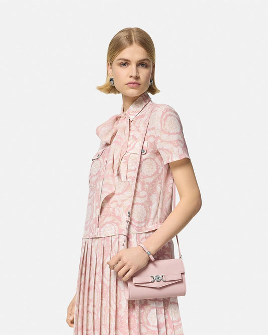 Woman wearing a pink floral outfit with a Versace Medusa '95 Crossbody Bag Light Pink 1014319 1A10795 1PT2P on a white background