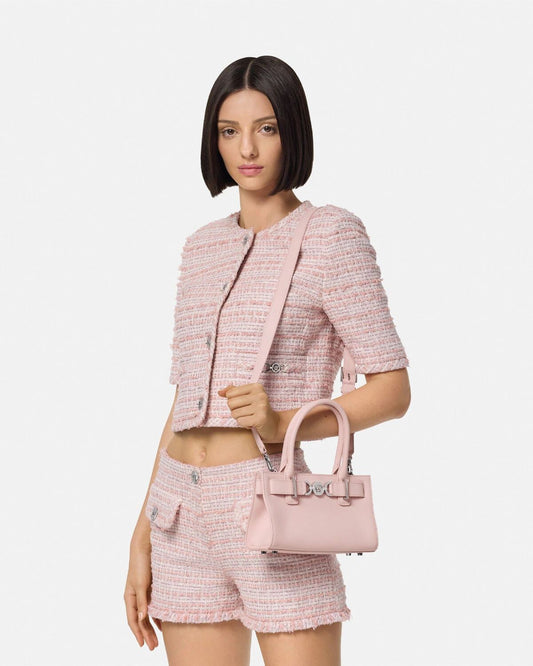 Woman wearing a pink tweed outfit with a Versace Medusa '95 Small Tote Bag Light Pink 1013169-1A10795_1PT2P on a white background
