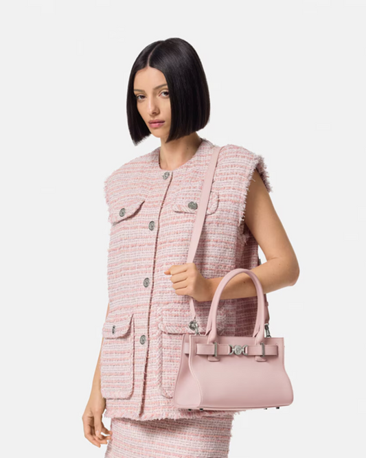 Woman holding a Versace Medusa '95 Tote Bag Light Pink 1013168-1A10795_1PT2P wearing a matching pink outfit on a white background