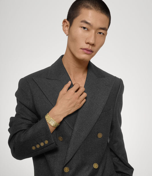 Man wearing a gray double-breasted suit with Vivienne Westwood Brunswick Olive Dial Gold Watch VV333LOLGD 8050164231903 on a plain background