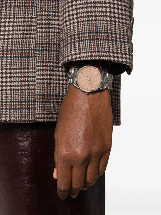 Close-up of a wrist wearing a Vivienne Westwood Little Seymour Peach Dial Silver Watch VV240PHSL with a checkered coat sleeve.