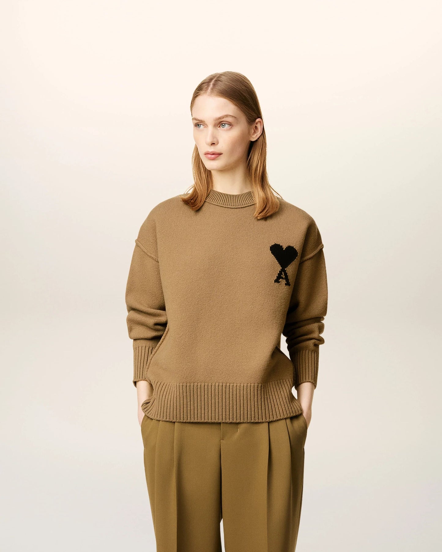 Woman wearing a Ami De Coeur Crewneck Brown Wool Sweater UKS838.018.288 with a black logo on a beige background