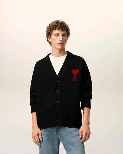 Person wearing a Wool Ami De Coeur Cardigan Black/Red – Felted Merino Wool UKC367.018.009 with a red heart logo on a plain background