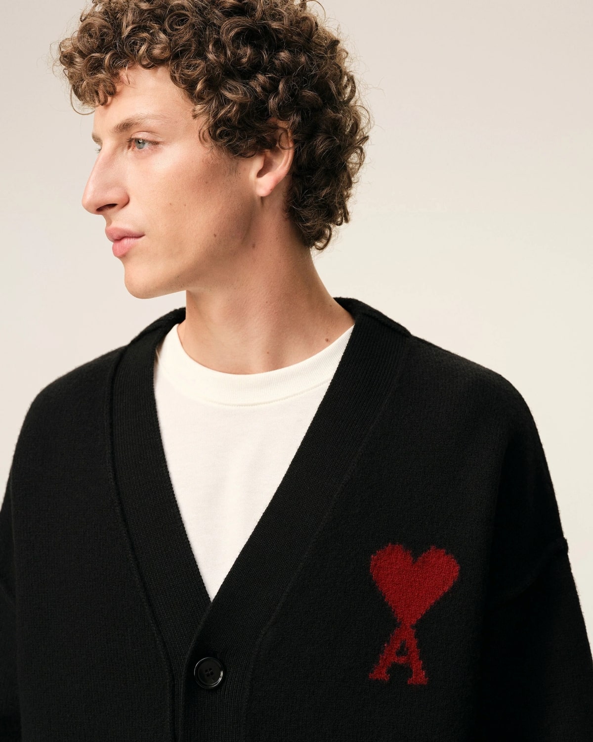 Person wearing a Wool Ami De Coeur Cardigan Black/Red – Felted Merino Wool UKC367.018.009 with a red heart and letter 'A' emblem on a plain background