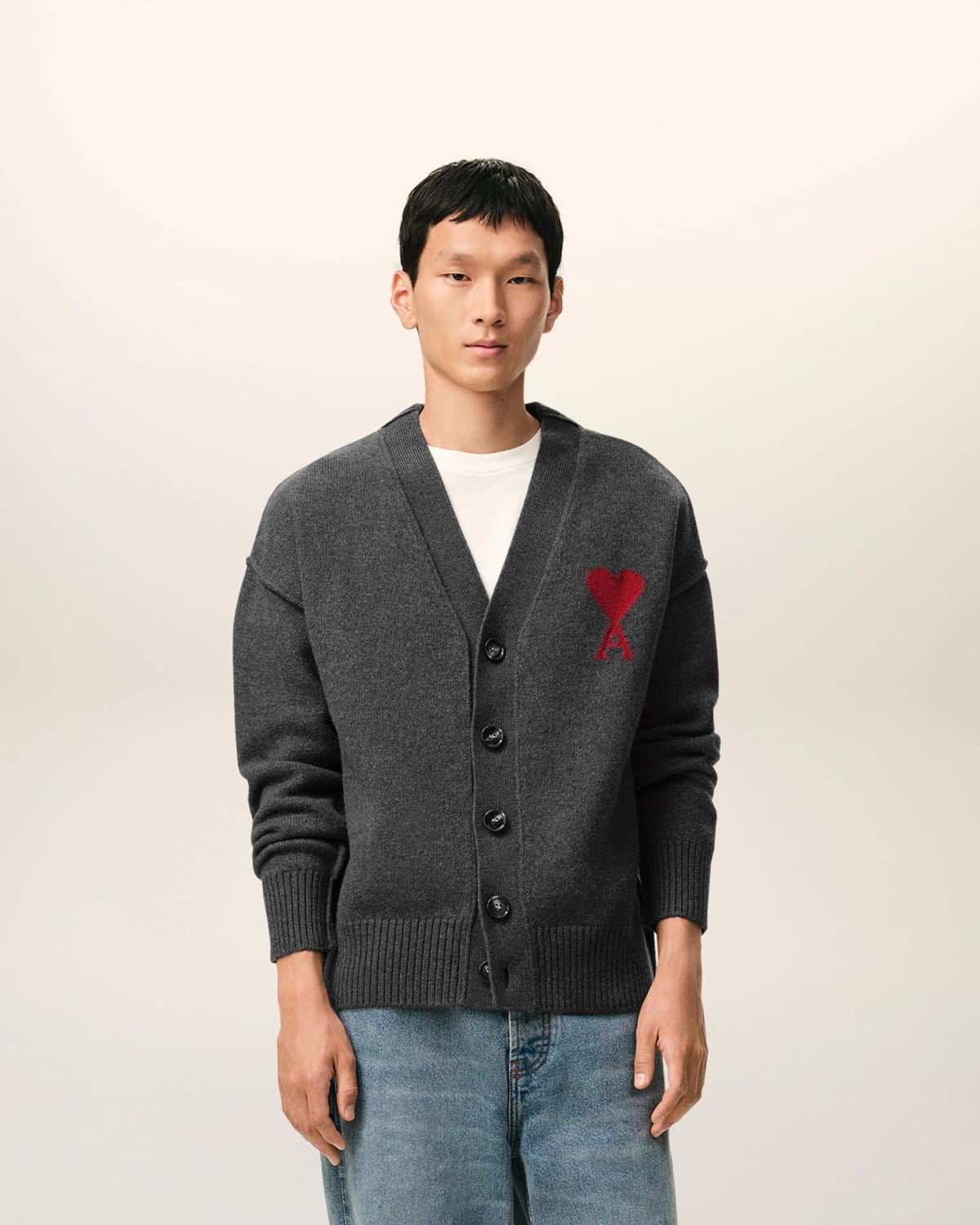 Man wearing a Grey Wool Ami De Coeur Cardigan Heather Grey/Red UKC367.018.084 with a red heart emblem on a light background