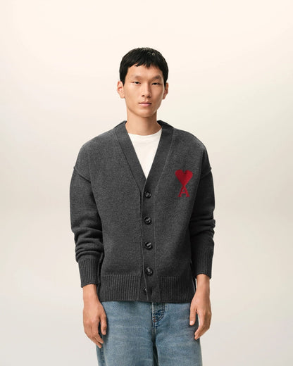 Man wearing a Grey Wool Ami De Coeur Cardigan Heather Grey/Red UKC367.018.084 with a red heart emblem on a light background