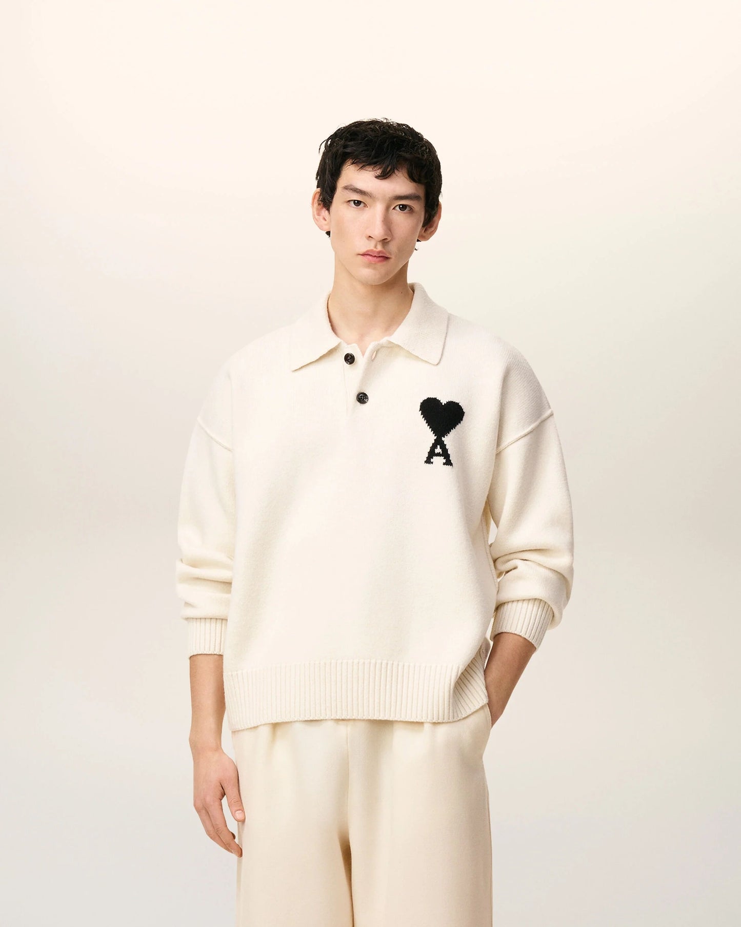 Person wearing a Ami De Coeur White Wool Polo Sweater UPL409.018.151 with a black logo on a white background