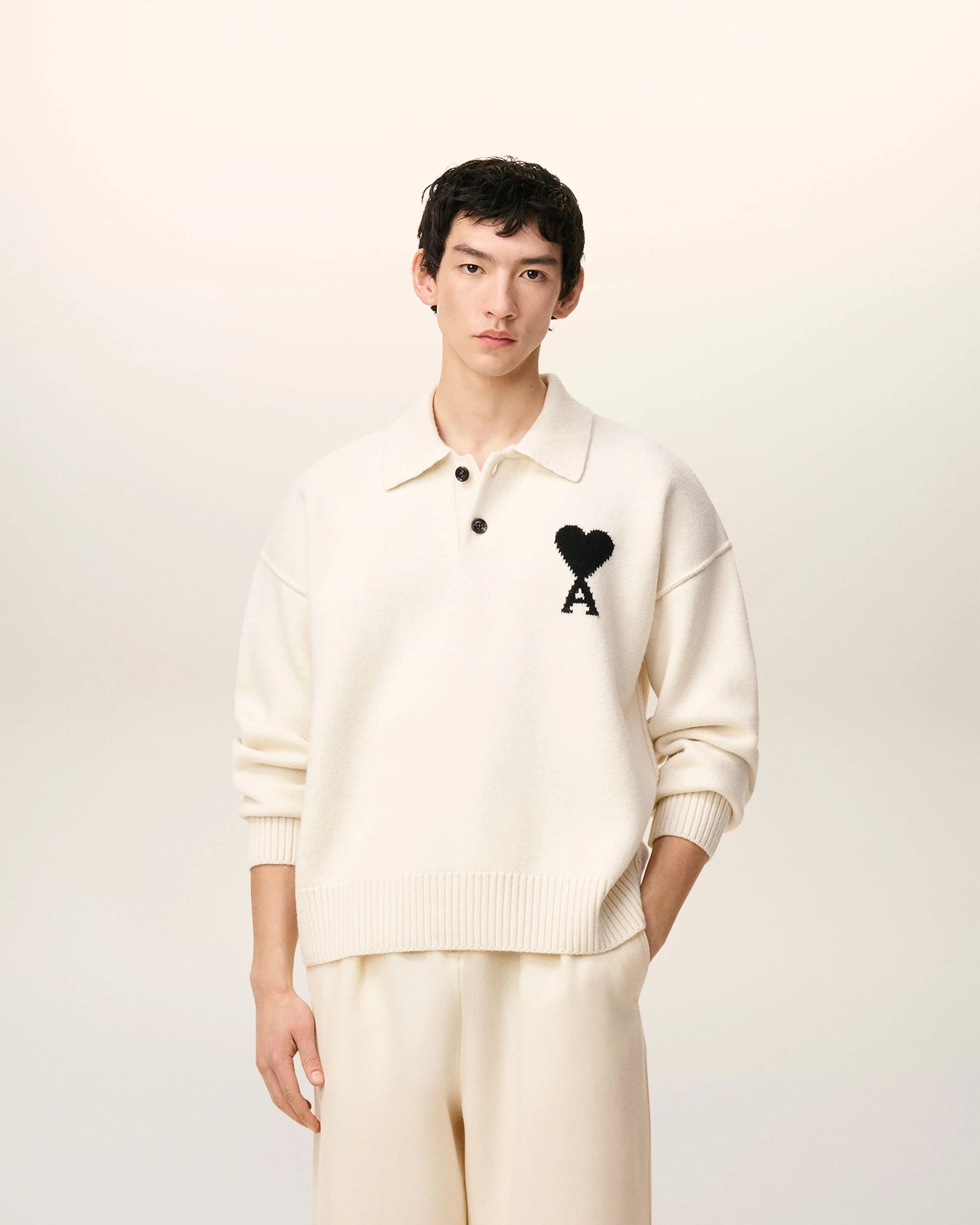 Person wearing a Ami De Coeur White Wool Polo Sweater UPL409.018.151 with a black logo on a white background