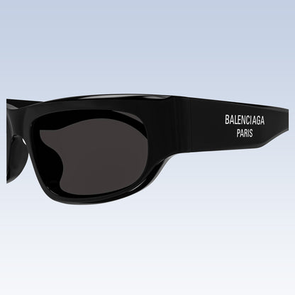 Balenciaga BB0388S 001 Black Rectangular Sunglasses with dark lenses and white logo text on the temple, shown against a light blue gradient background.
