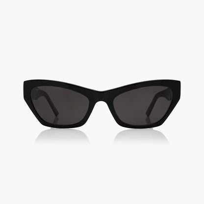 Balenciaga BB0447S Black Cat-Eye Sunglasses with dark tinted lenses, shown from the front on a light gray background with a soft reflection below.