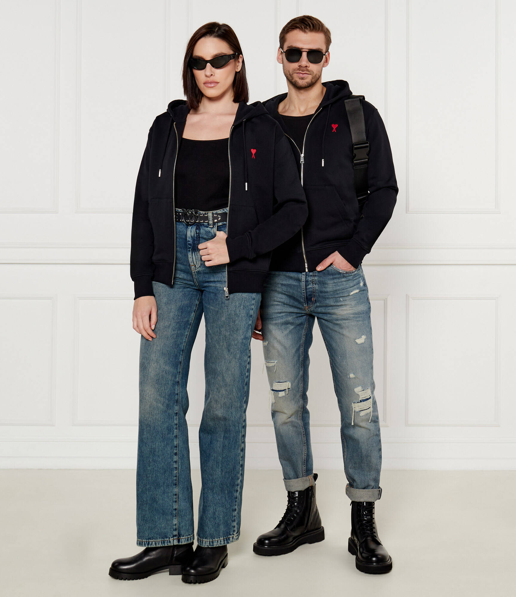 Two people wearing matching Black Cotton Ami de Coeur Zipped Hoodie BFUSW435.730.001 and blue jeans against a white background