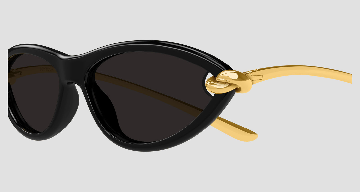 Bottega Veneta BV1390S Gold Knot Cat-Eye Sunglasses with dark lenses and gold metal temples featuring a knot detail, shown against a light gray background.
