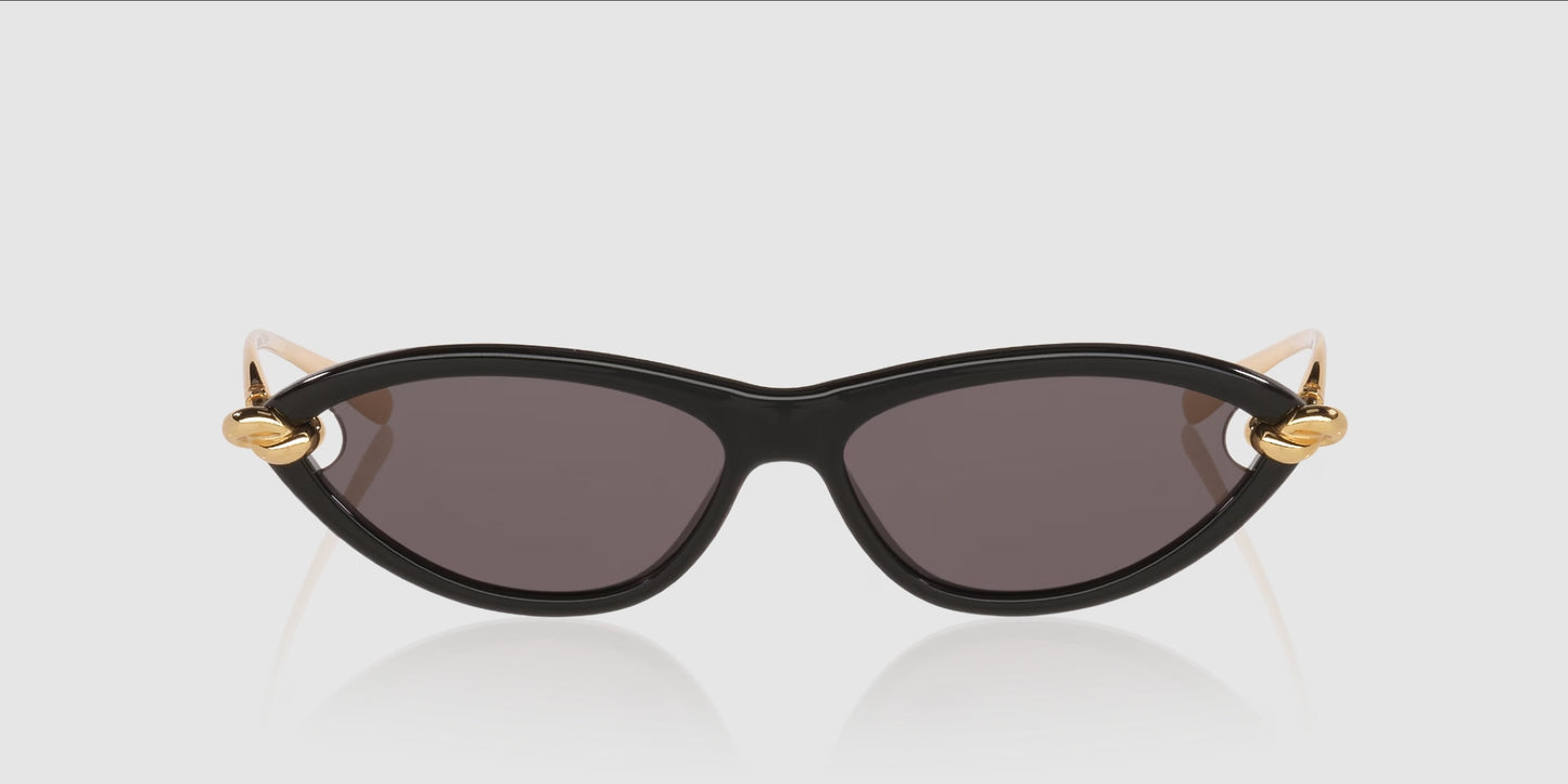 Bottega Veneta BV1390S Gold Knot Cat-Eye Sunglasses with dark lenses and gold metal accents on the temples, shown against a light gray background.
