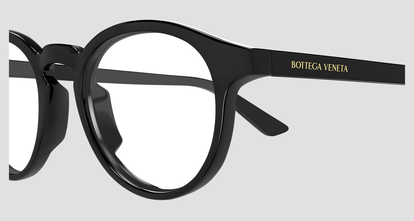 Close-up of a pair of Bottega Veneta BV1420O Black Round Eyeglasses with glossy black frames and gold lettering on the temple arm, set against a light gray background.