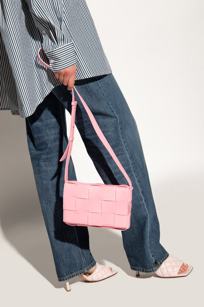 Person holding a Bottega Veneta Small Cassette Shoulder Bag Pink 578004VMAY15832 against a neutral background