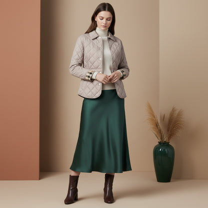 Woman wearing a Burberry Cawthorne Quilted Jacket Light Taupe 81114571, white shirt, green satin skirt, and brown boots in a studio setting.