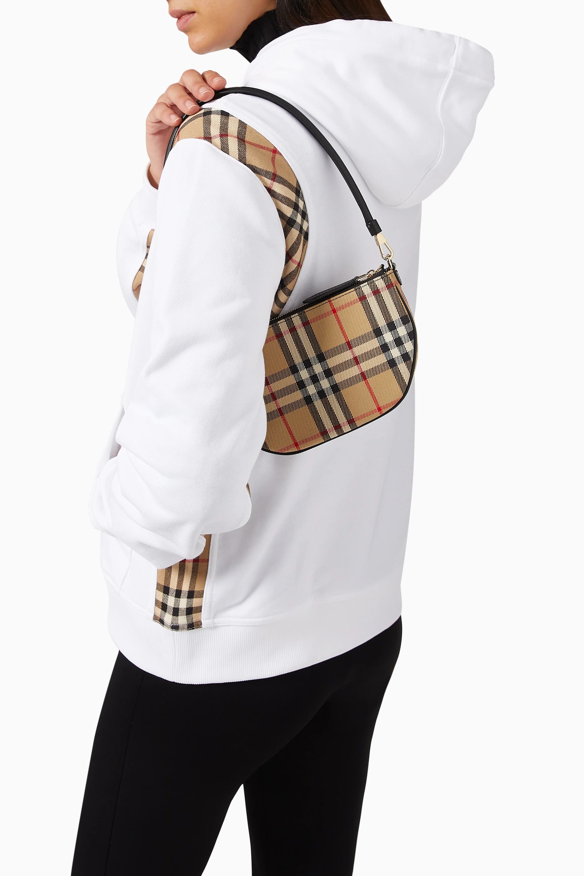 Person wearing a white hoodie with a Burberry Vintage Check Olympia Pouch In Canvas Archive Beige 81114131 over their shoulder on a white background