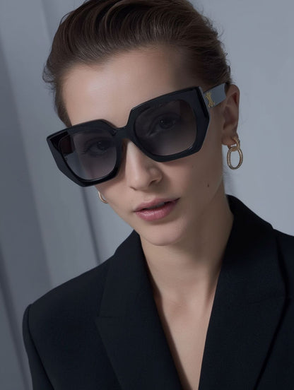Woman wearing Celine CL40239F 01F Butterfly Triomphe Sunglasses In Acetate and a black blazer against a gray background