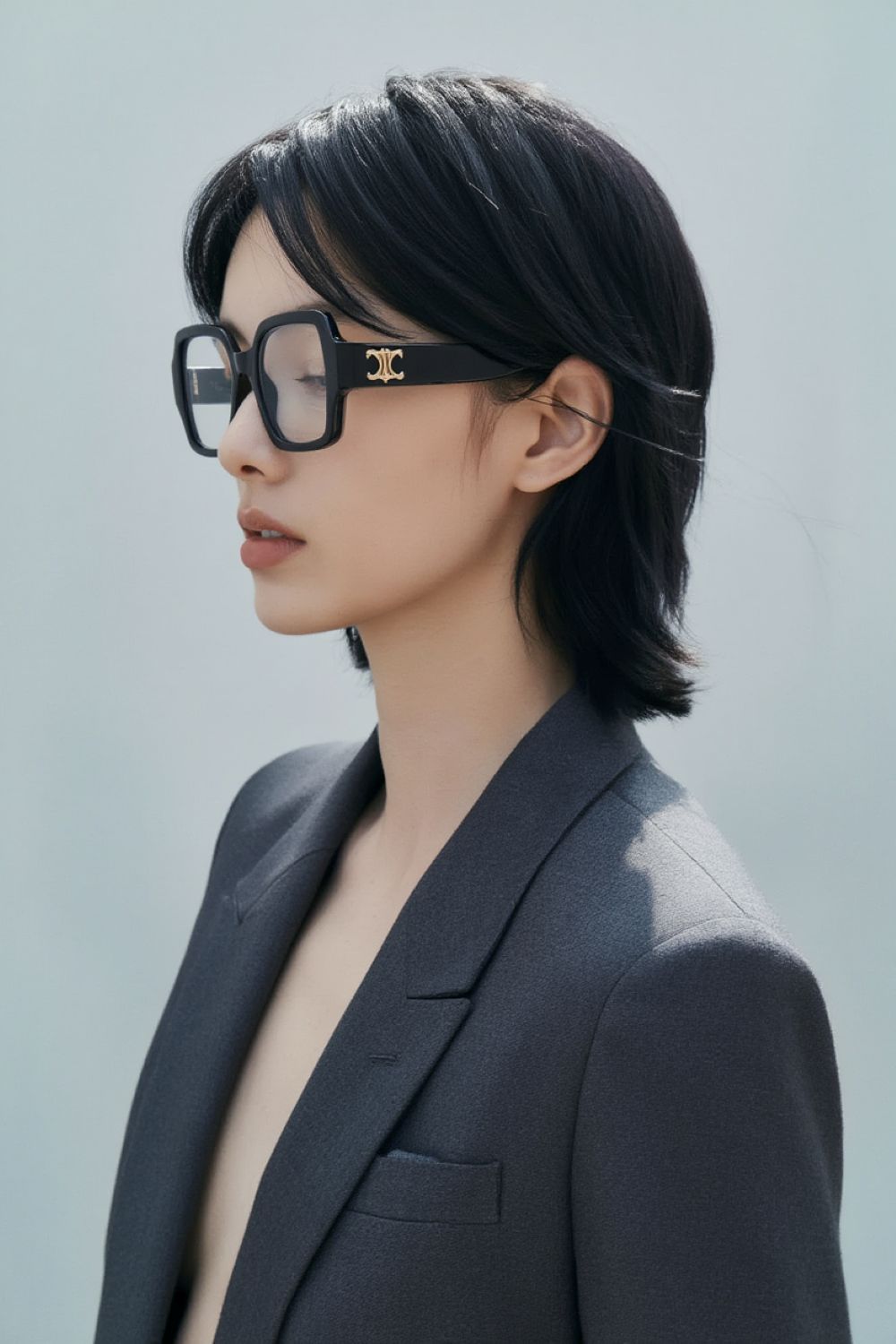 Person wearing Celine CL50131F 001 Square Eyeglasses and a gray blazer against a light background