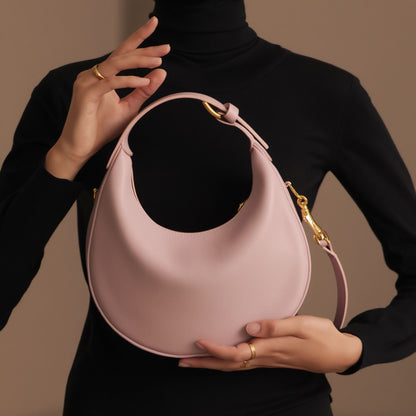 Person holding a Celine Teen Celine Lulu in Grained Calfskin Bleached Pink 120723ENY.25BD with gold accents against a neutral background