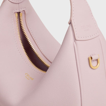 Close-up of a Celine Teen Celine Lulu in Grained Calfskin Bleached Pink 120723ENY.25BD with gold zipper and handle on a white background